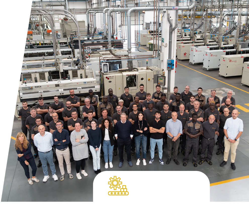 Foto di gruppo del team Eredi Baitelli in reparto, con linee produttive e macchinari sullo sfondo.