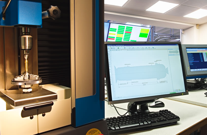 Postazione di controllo dimensionale con macchina di misura e monitor che mostra il profilo di un componente tornito.