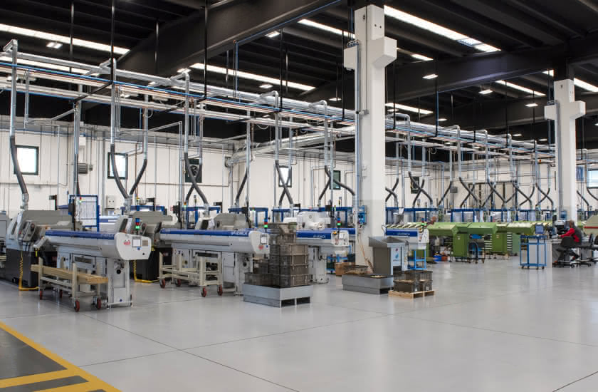 Interno del nuovo sito produttivo Eredi Baitelli a Erbusco, con file ordinate di torni automatici e sistemi di aspirazione.